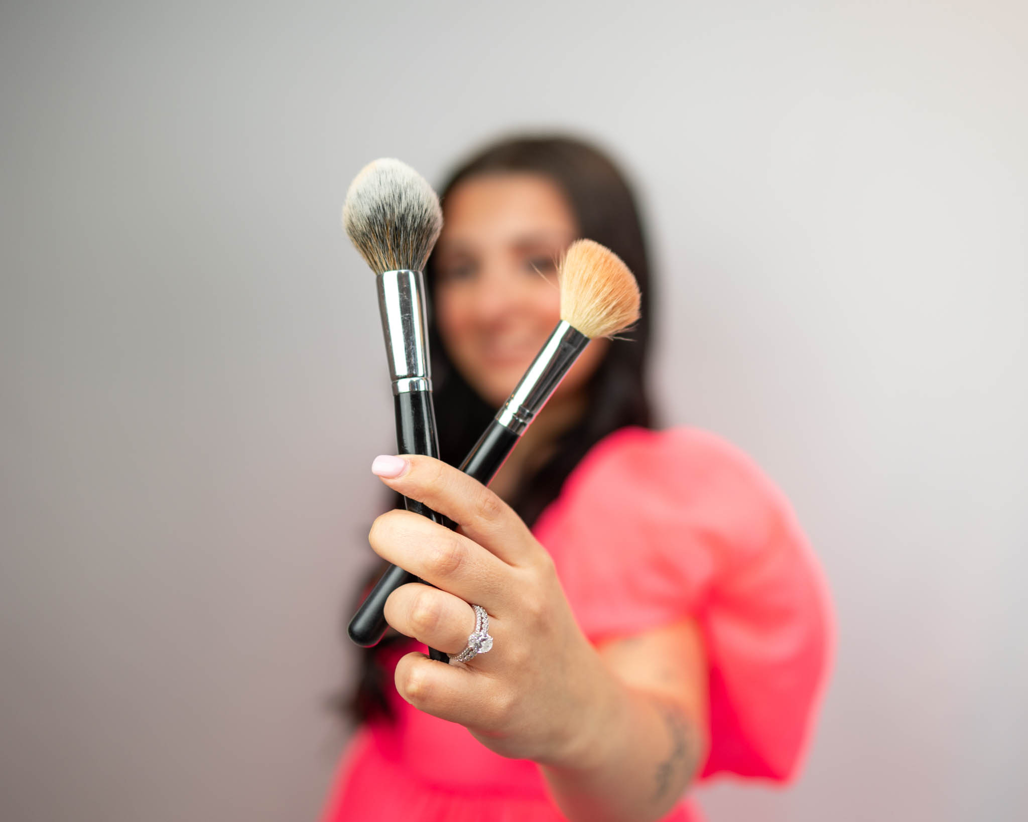 photo owner holding 2 makeup brushes